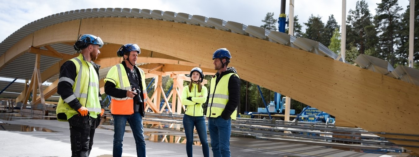 Projektteam på plats framför bygget av sportcentret. Foto: Moelven